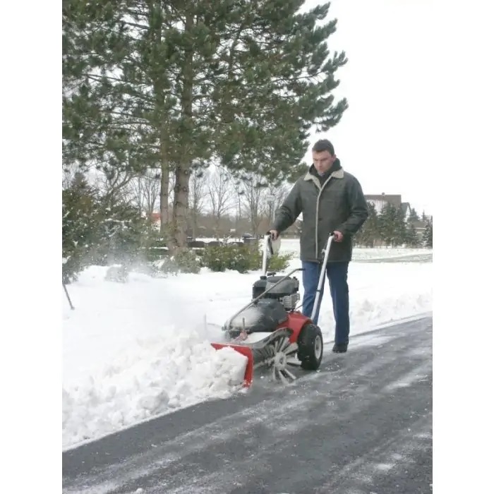 Mężczyzna odgarniający śnieg z drogi zamiatarką marki Tielbuerger